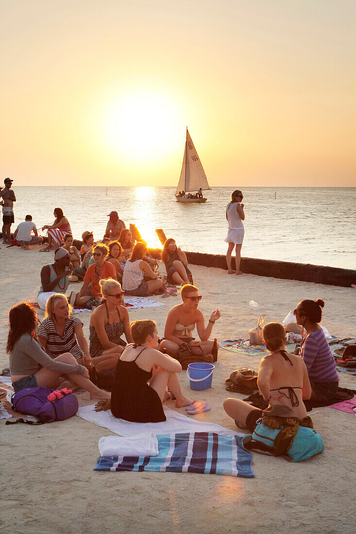 BELIZE, Caye Caulker, tourists enjoy the beach and sunset at the Lazy Lizard Bar