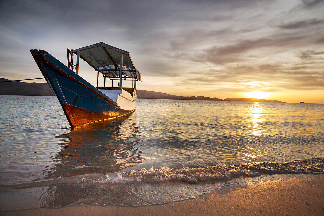 INDONESIA, Flores, Riung, a boat floats in the Flores Sea at sunset on Rutong island