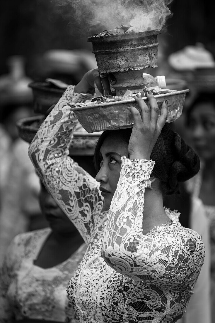 A Young Woman At A Religious Ceremony Carrying A Smoking Offering On Her Head; Bali, Indonesia
