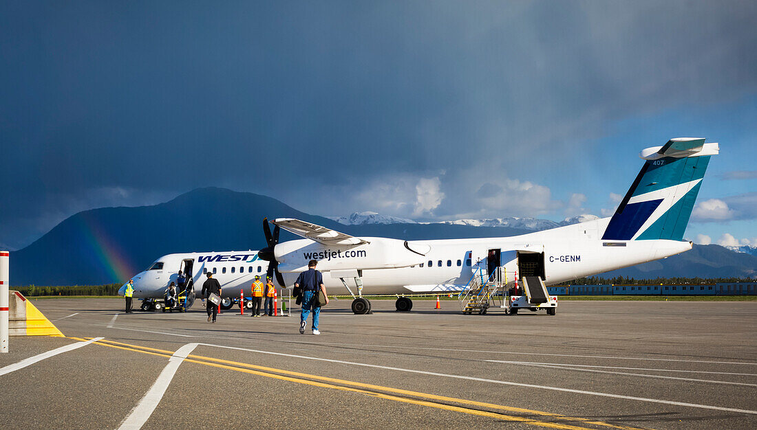 Rainbow Over The Terrace Kitimat Airport As Passengers Load A Plane On The Tarmac; Terrace, British Columbia, Canada