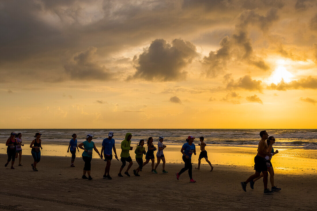 Runners race on the beach at sunrise during the 2017 USA Beach Running Championships; Cocoa Beach, Florida, United States of America