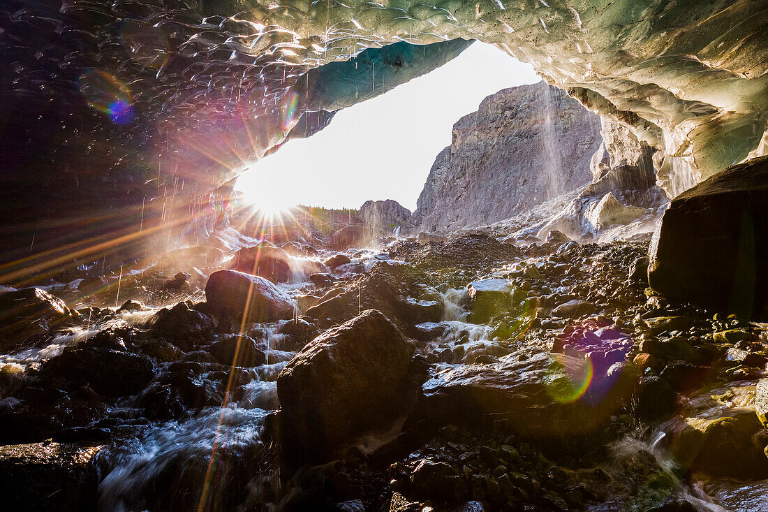 The sun shines into a cave beneath the ice of Root Glacier in Wrangell-St. Elias National Park; Alaska, United States of America