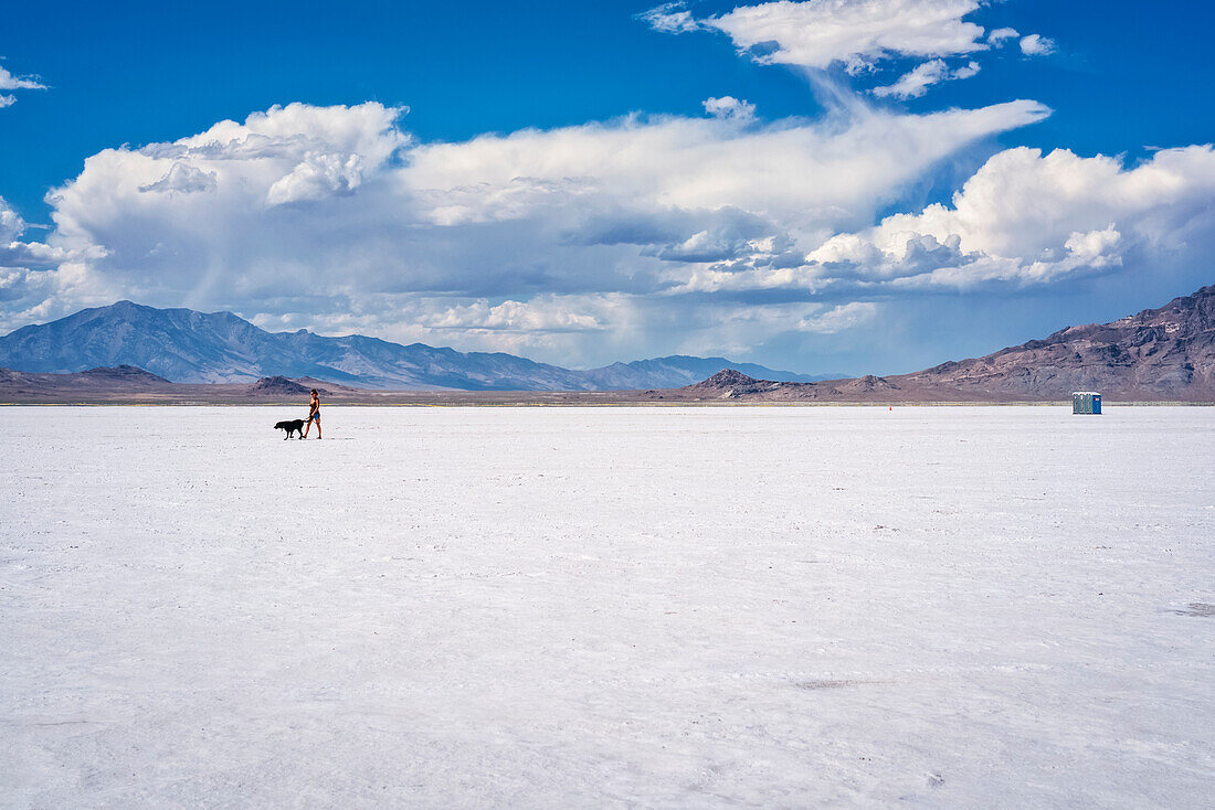 Woman walks her dog on Bonneville Salt Flats; Wendover, Utah, United States of America