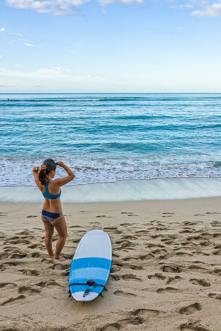 Young female surfer prepares on the beach to go out to the water; Honolulu, Oahu, Hawaii, United States of America