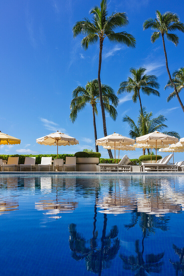 Halekalani Pool at Waikiki with palm trees and umbrellas reflected in the water; Honolulu, Oahu, Hawaii, United States of America