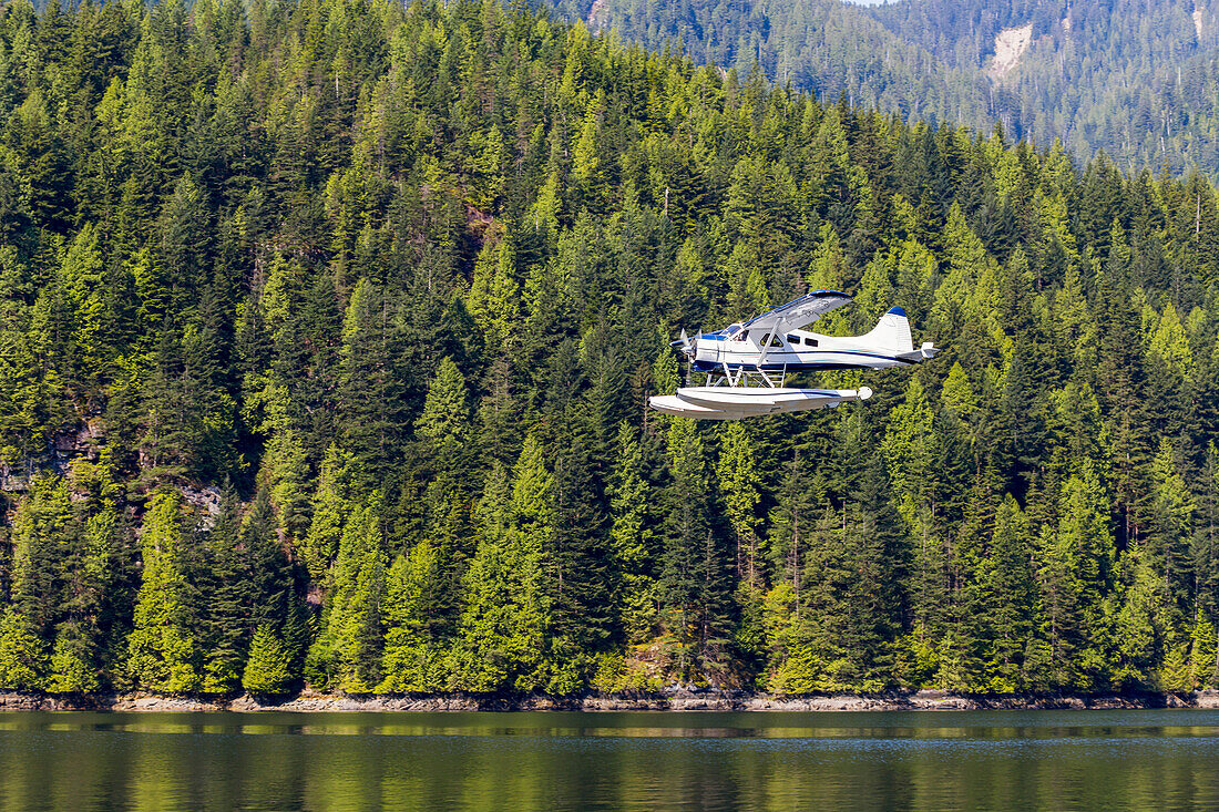 A float plane travels low above the ocean on a scenic tour of the forest and mountains near Vancouver; British Columbia, Canada