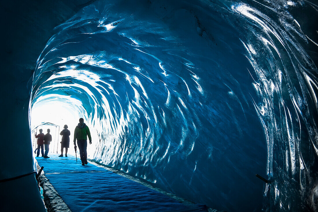 Family of tourists step into ice cave under Mer de Glace Glacier; Chamonix-Mont-Blanc, Haute-Savoie, France