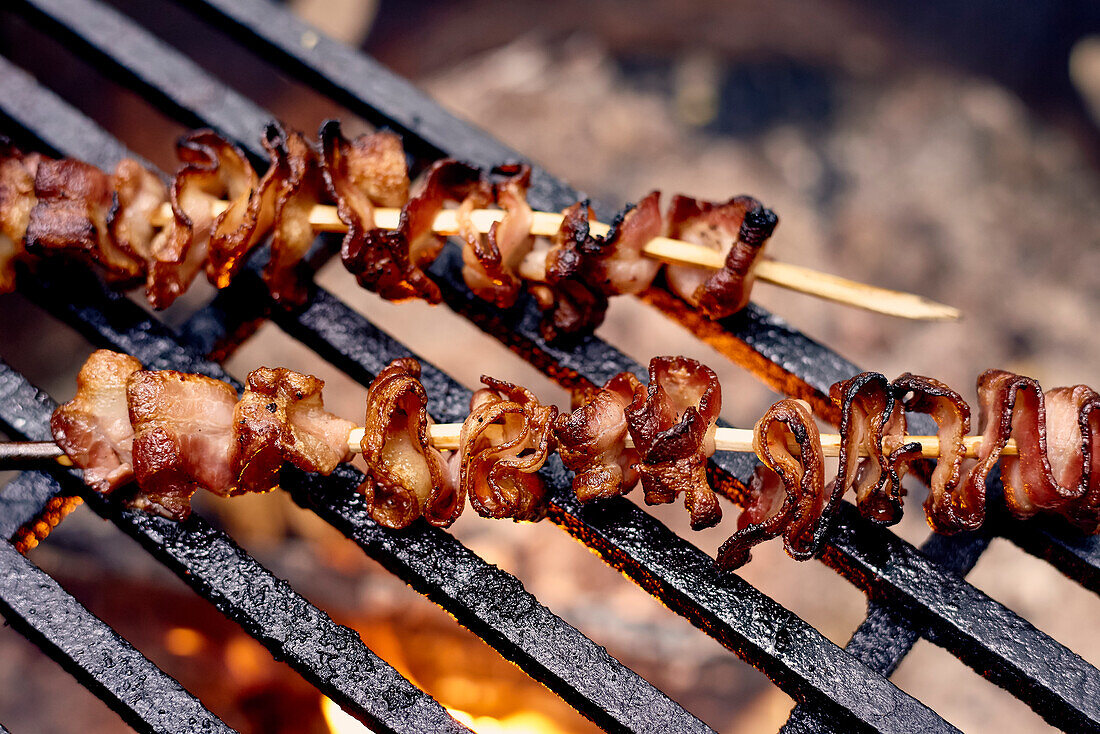 Bacon Skewers Cooking Over A Flame On A Grill; Ontario, Canada