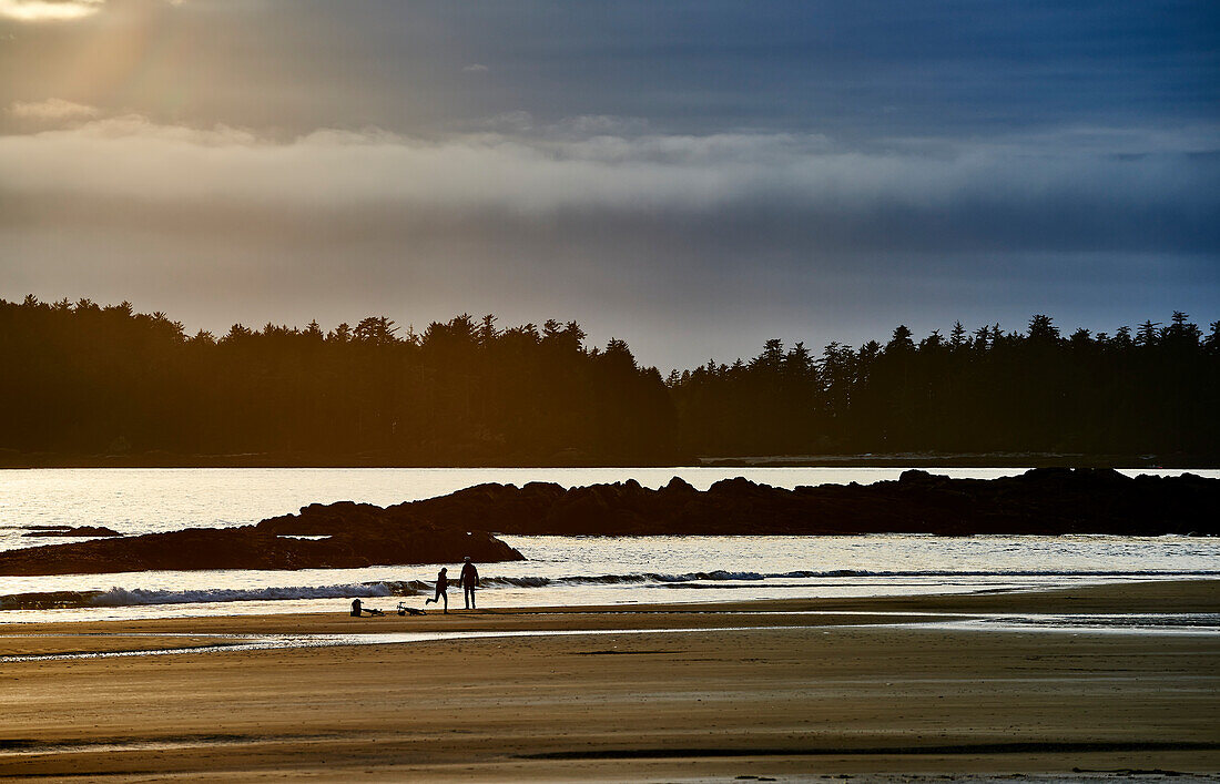 Silhouette Of A Couple And Their Bikes On Mackenzie Beach At Sunset; Tofino, British Columbia, Canada
