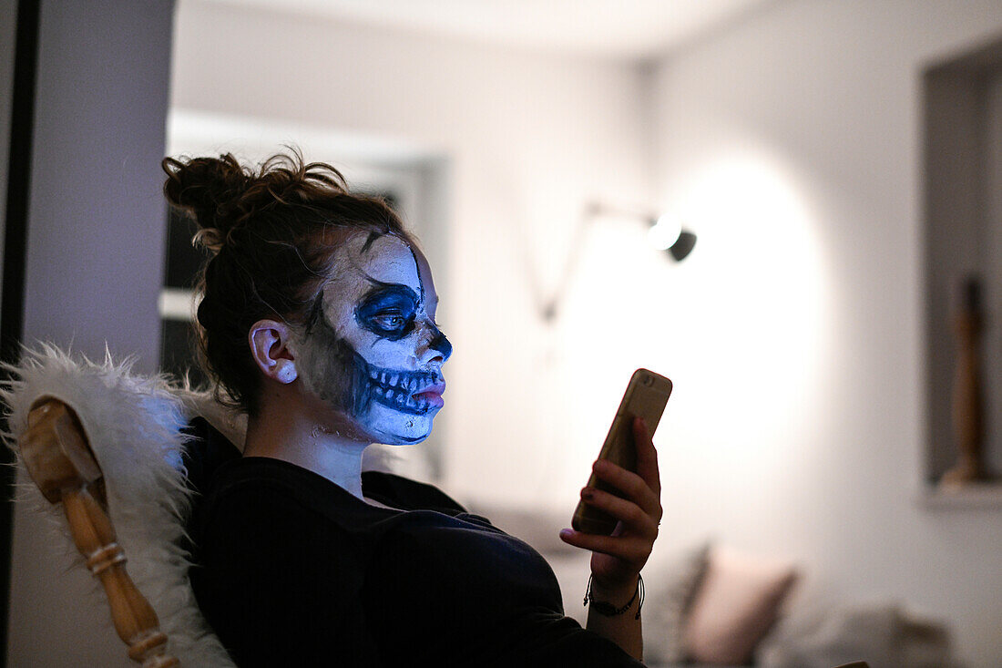 Geschminktes Mädchen mit Handy an Halloween, Hamburg, Deutschland
