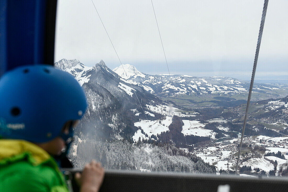 Junge schaut aus einer Berggondel, Charmey, Schweiz