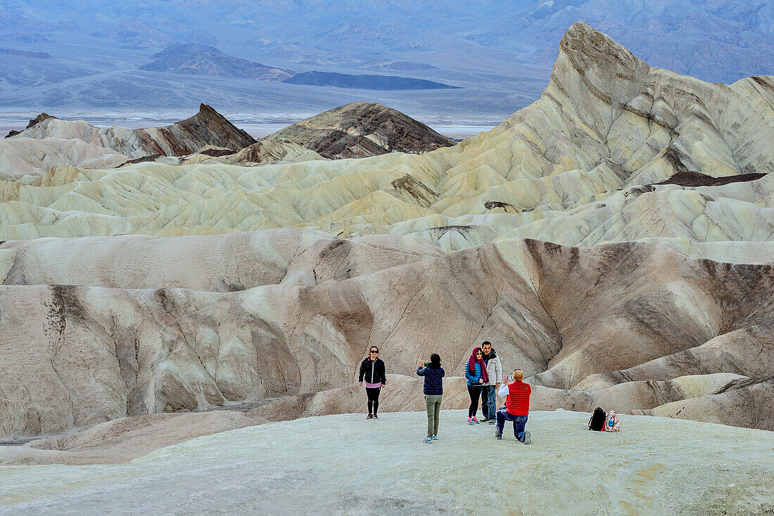 Several persons posing in front of colourful badlands at Death Valley, Death Valley National Park, California, USA
