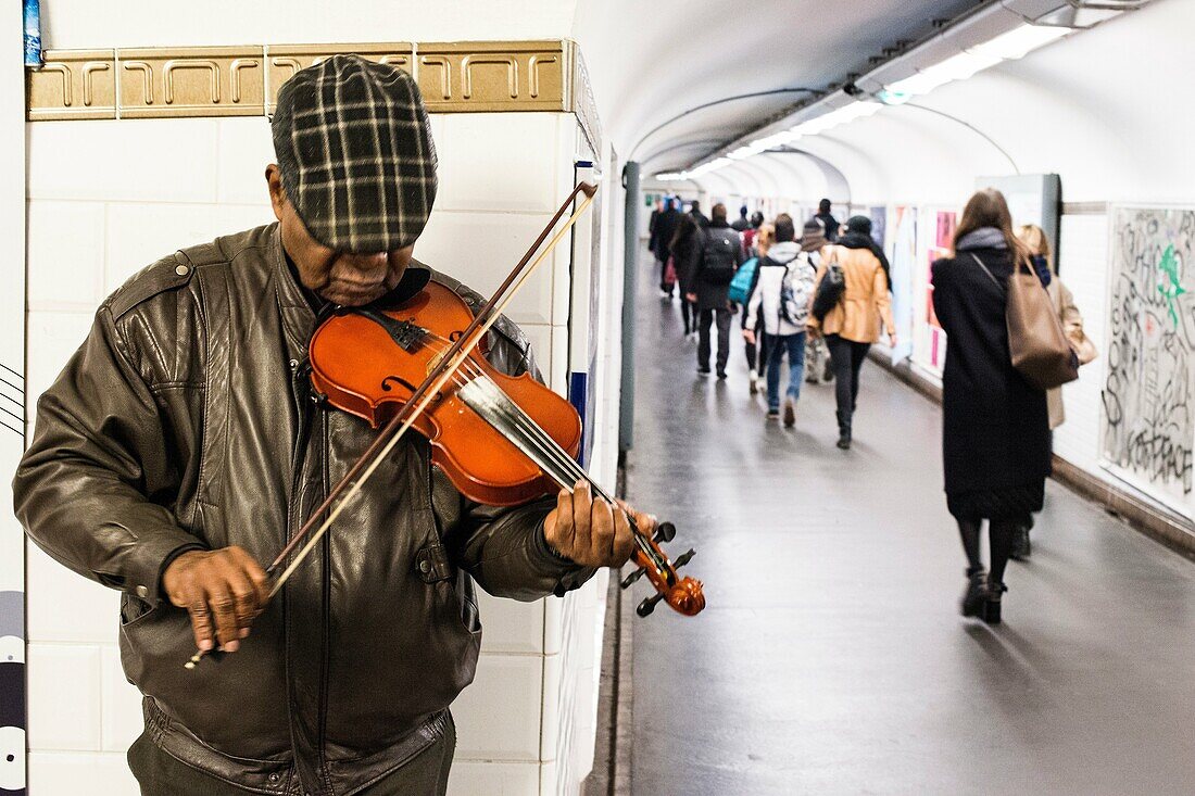 Paris, France. Mature adult male musician performing his music inside Chatalet Subway Station. Music in the French Underground system is wide spread, giving commuters an extra good experience during their commutes. And it provides an extra source of incom