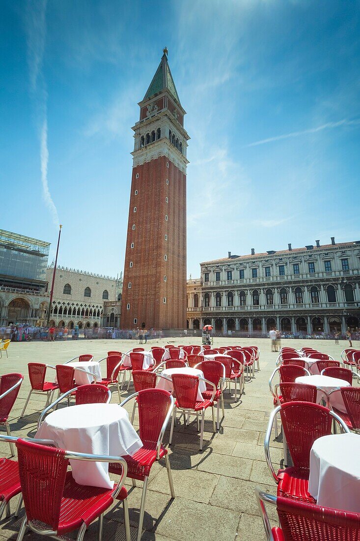 Europe, Italy, Veneto, Venice. The bell tower and the square of St. Mark with the cafe's chairs and tables.