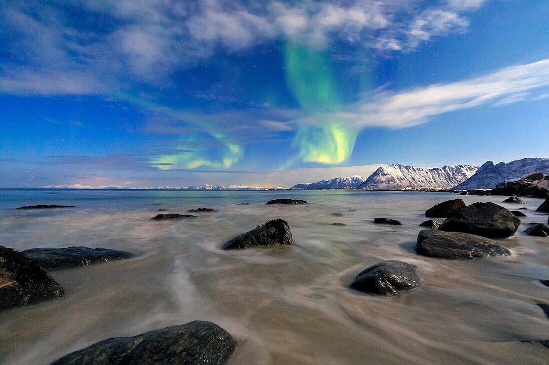 Northern Lights illuminate the landscape around Gymsøyand and the snowy peaks. Lofoten Islands Northern Norway Europe.