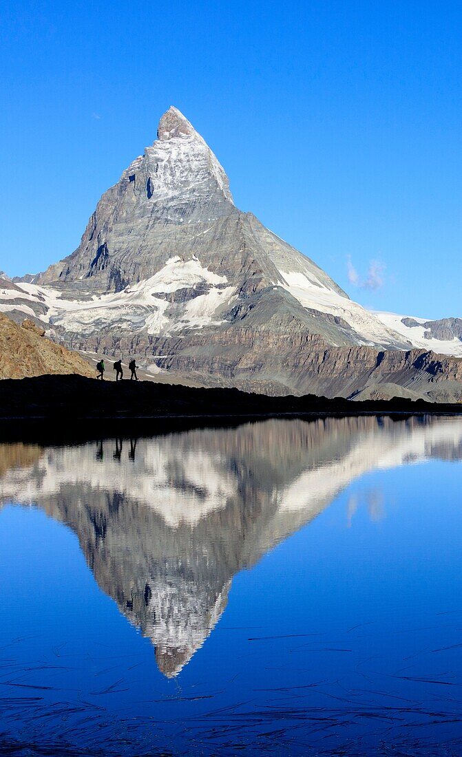 Hikers admire the Matterhorn reflected in Lake Stellisee Zermatt Canton of Valais Pennine Alps Switzerland Europe.