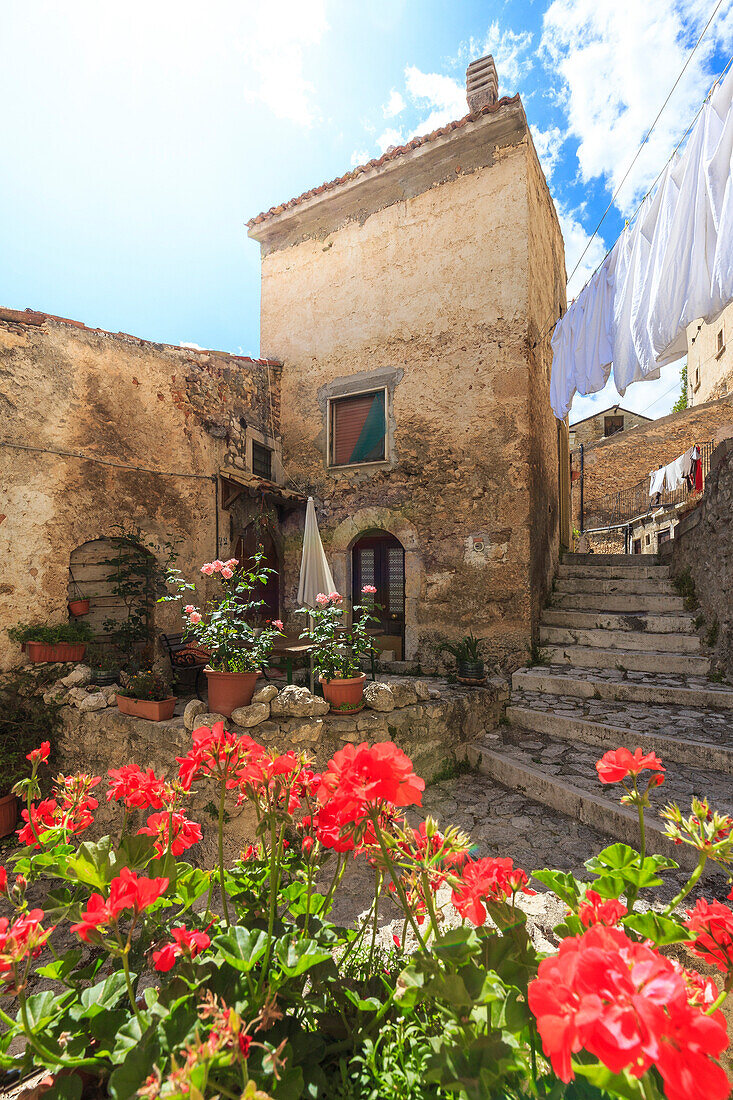 The sun illuminates a flowered balcony in the historic center of Santo Stefano di Sessanio, Abruzzo, Italy.