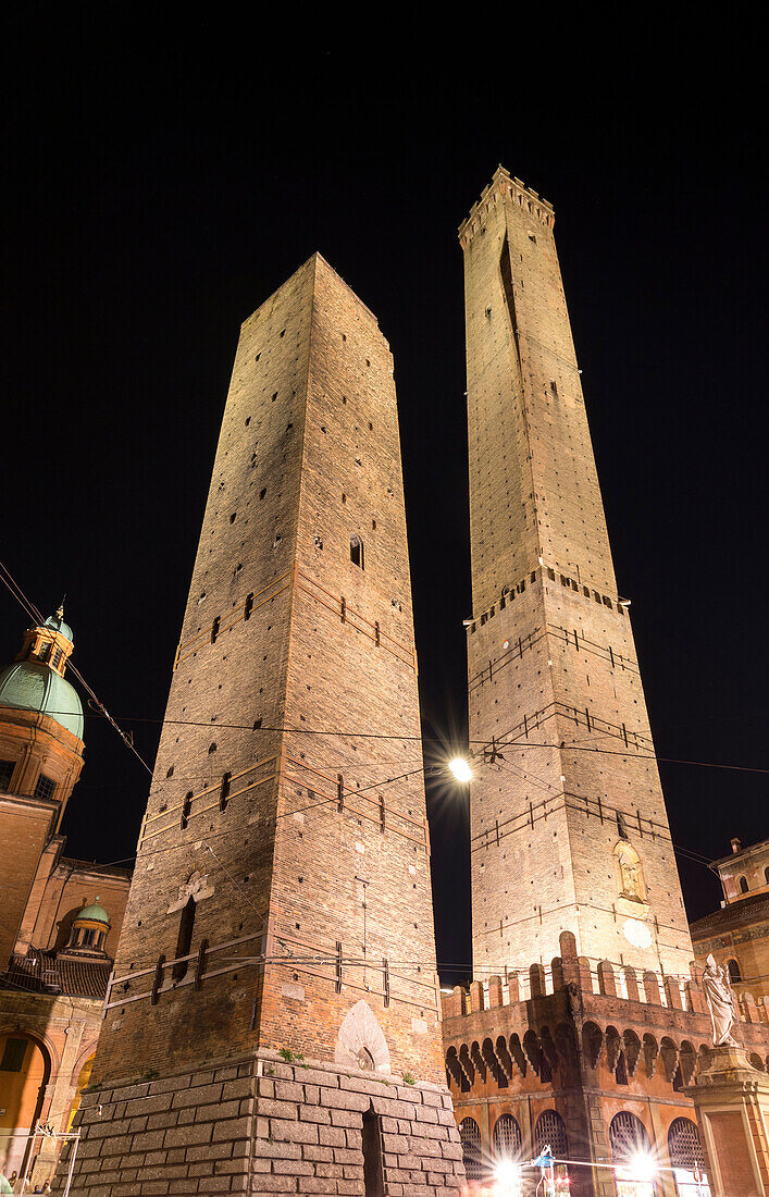 View of the Torre degli Asinelli and Torre della Garisenda from Piazza di Porta Ravegnana square at night. Bologna, Emilia Romagna, Italy.