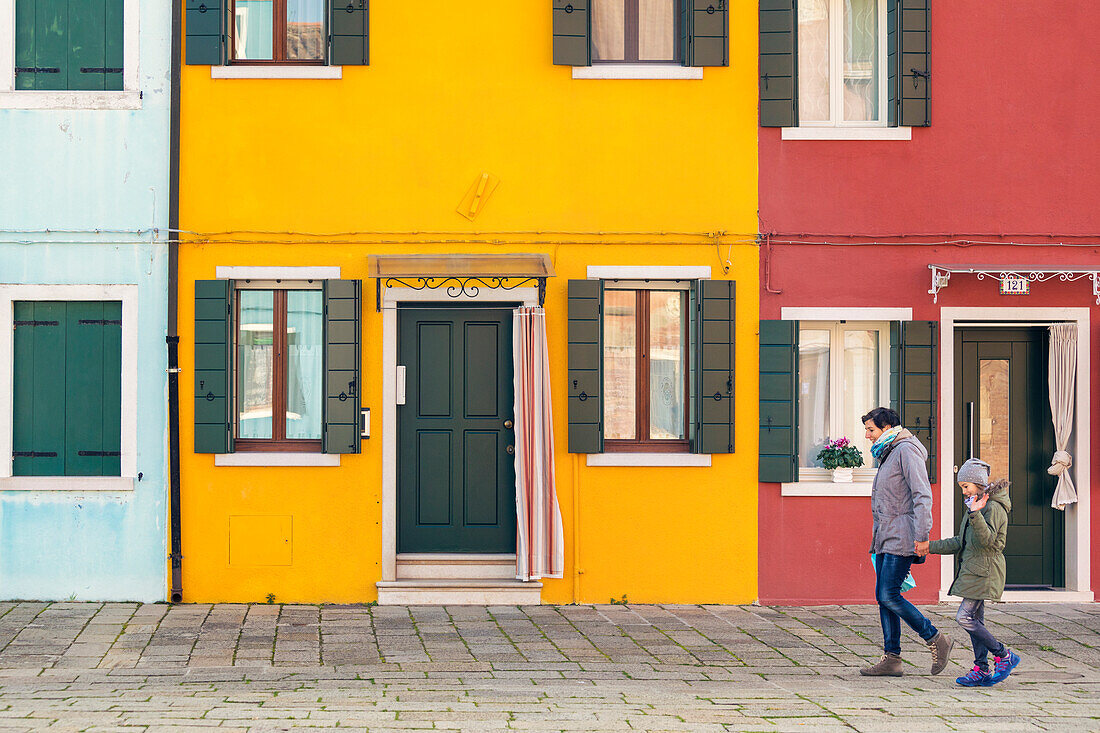 tourists walk in front of the colorful houses of Burano, Venice, Veneto, Italy
