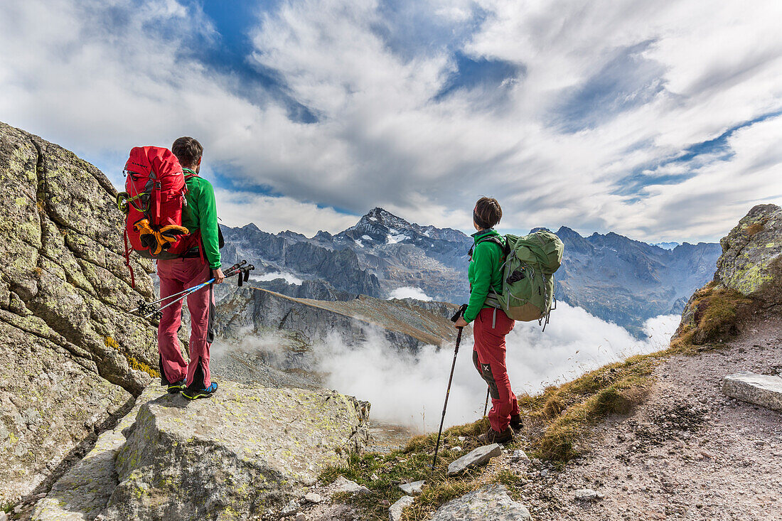 Lombardy, Italy, Trekkers at Qualido pass, in the background Disgrazia peak. Masino valley