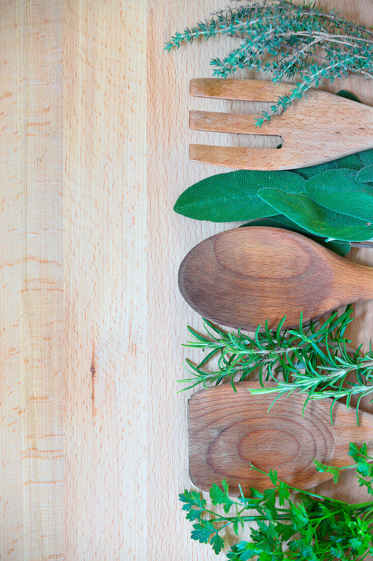 Wooden cooking utensils among aromatic herbs: parsley, sage, thyme, rosemary, Lombardy, Italy