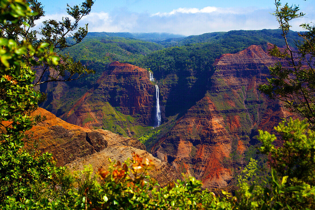 Waimea Canyon Falls and lush foliage on rugged cliffs and mountains; Waimea, Kauai, Hawaii, United States of America
