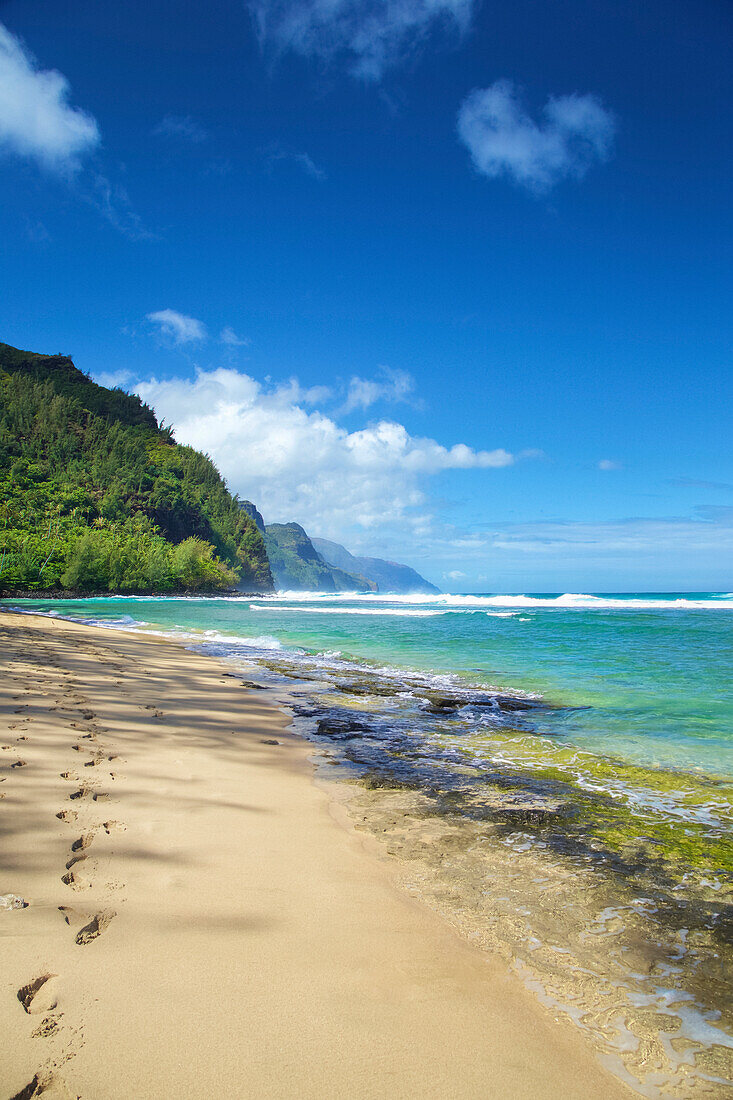 Footprints in the sand along the water's edge on the coastline of the Island of Hawaii; Haena, Island of Hawaii, Hawaii, United States of America