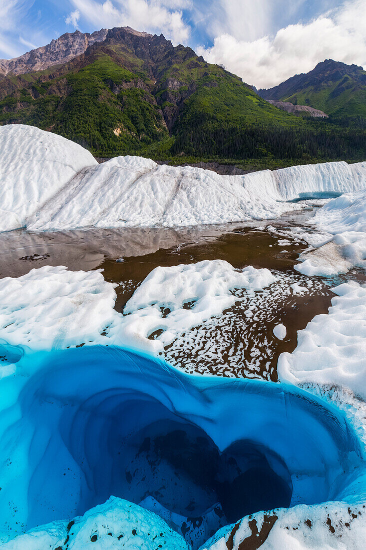 A pool of water on the surface of Root Glacier in Wrangell-St. Elias National Park resembles a heart shape; Alaska, United States of America