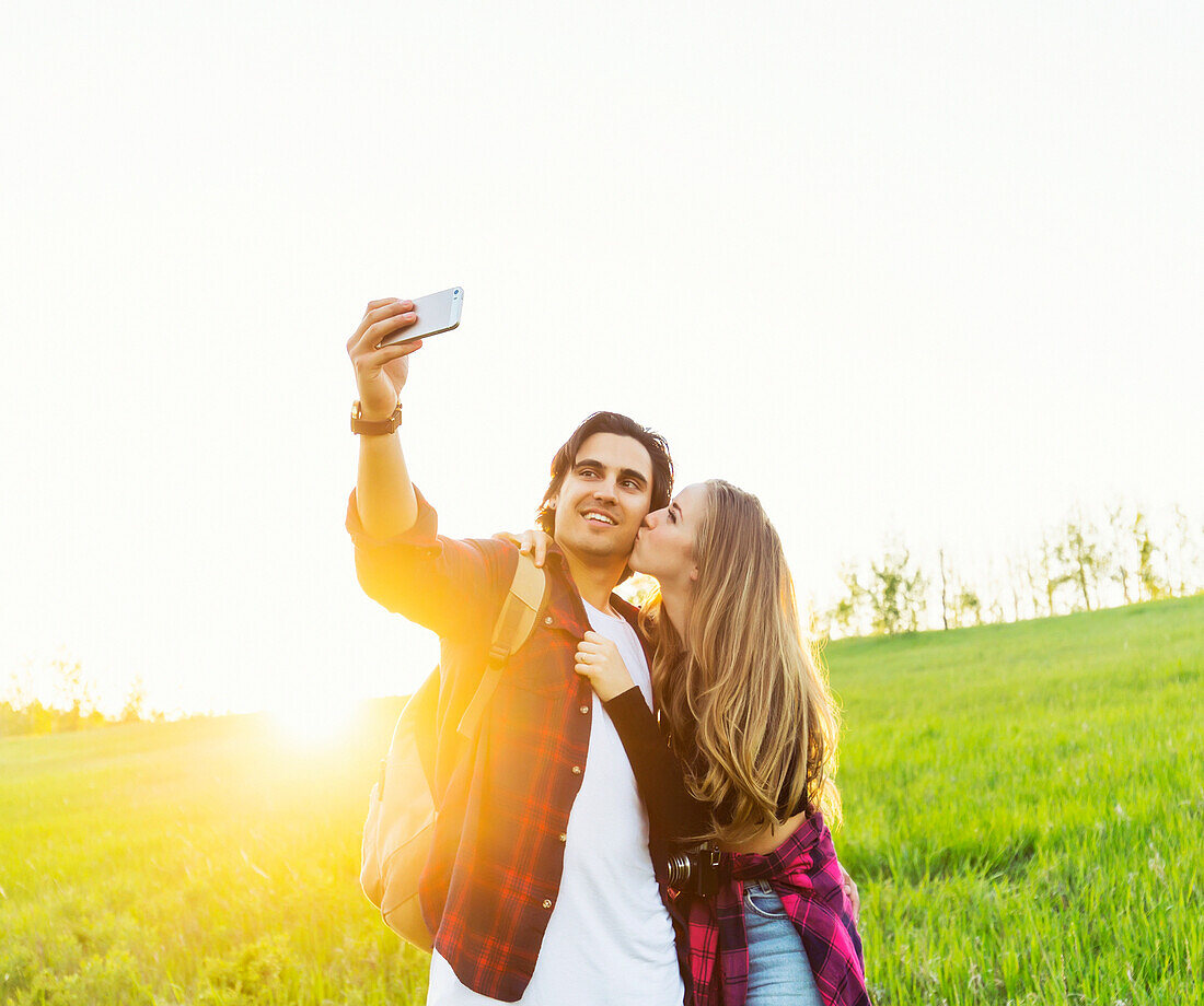Junges Paar in einem Park posiert für ein Selbstporträt mit ihrem Mobiltelefon; Edmonton, Alberta, Kanada