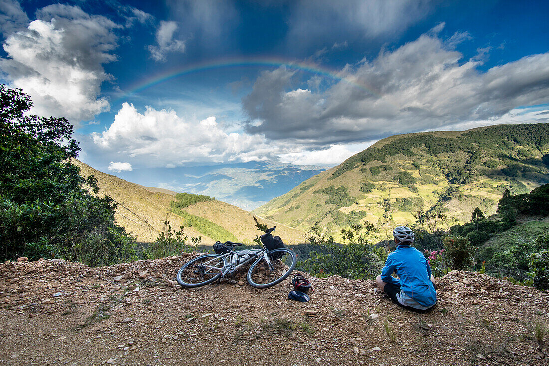 Woman cyclist taking break to look at rainbow on bike tour in San Mateo, Boyac, Colombia