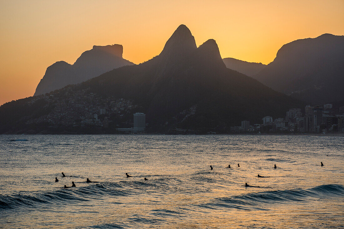 Surfers on water during sunset in Arpoador Beach, next to Ipanema in Rio de Janeiro, Brazil