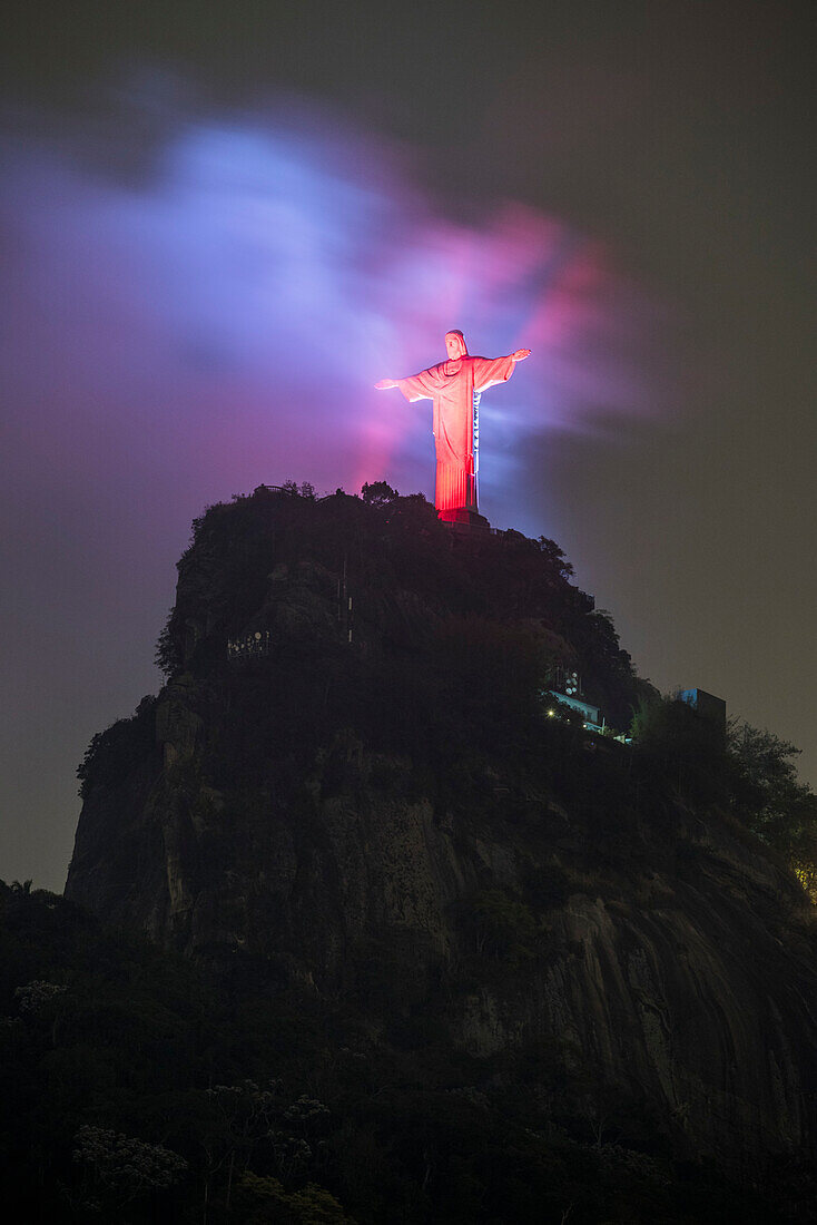 Christ the Redeemer statue with red lights during early night, Corcovado Mountain, Rio de Janeiro, Brazil