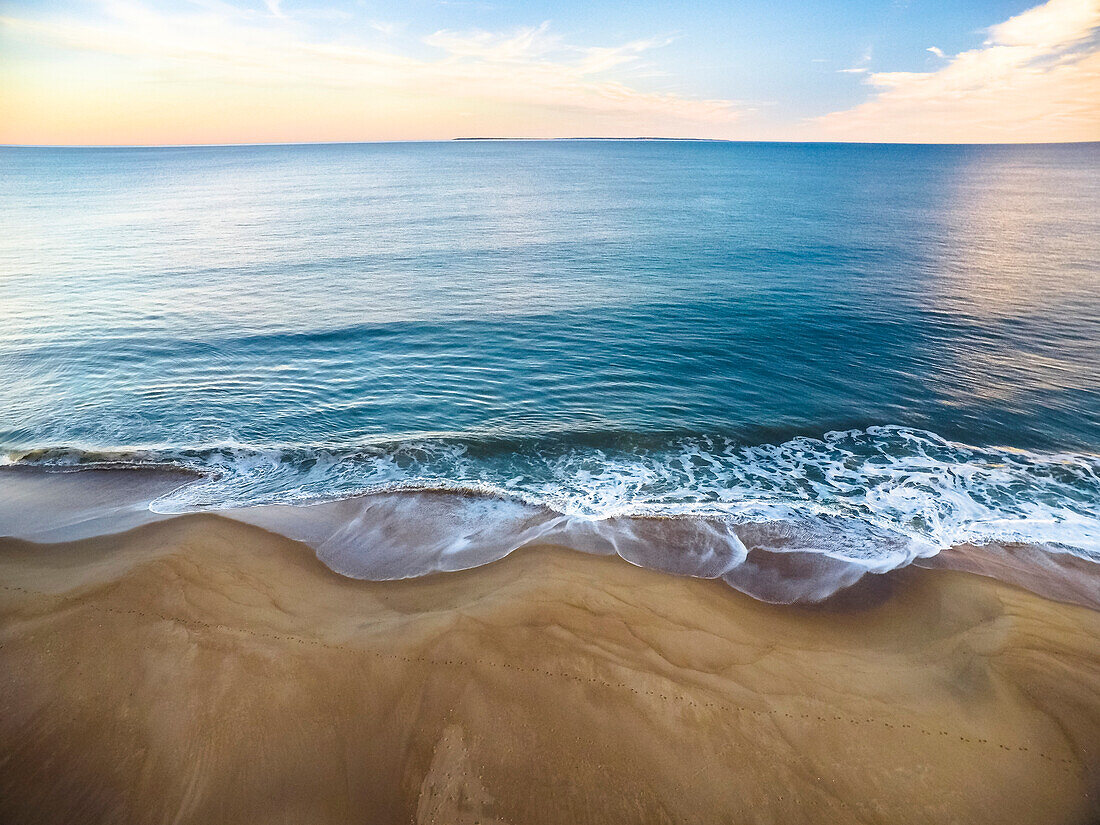Aerial drone photography over a Rhode Island beach in winter, during sunset