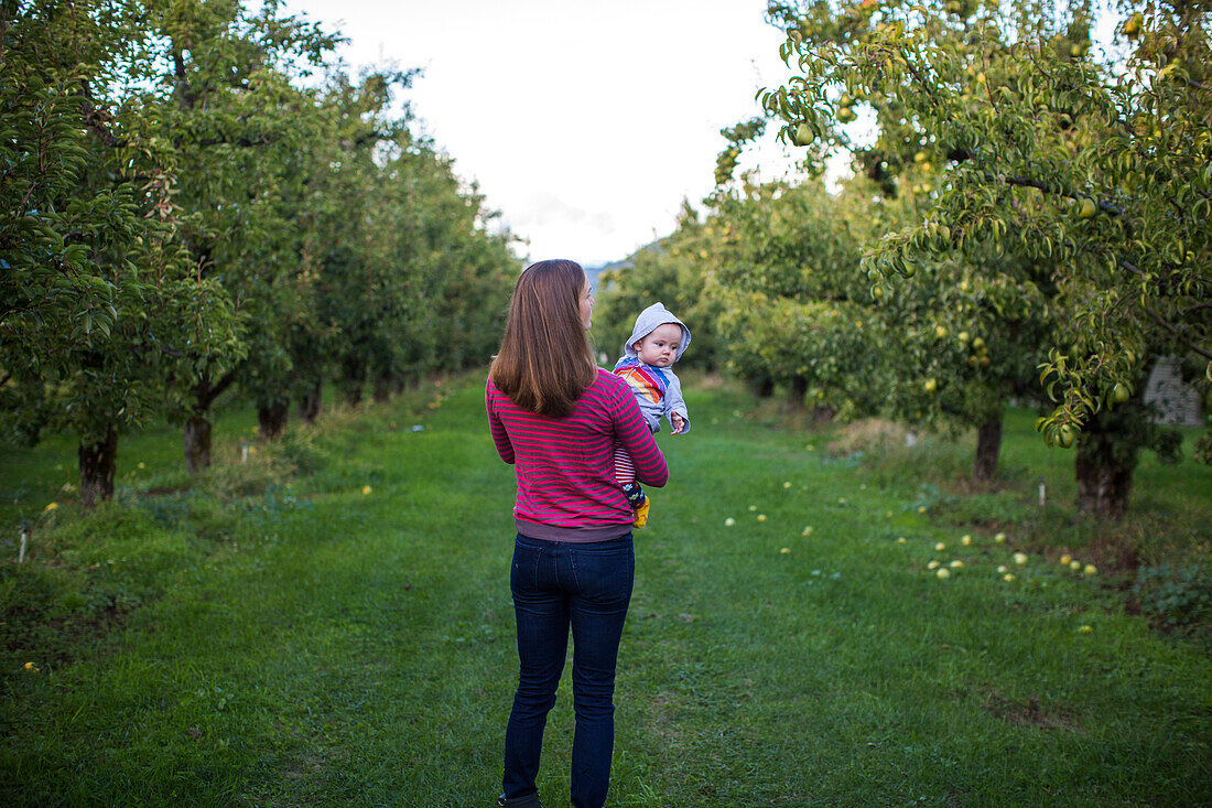 Mother with baby standing in orchard, Parkdale, Oregon, USA