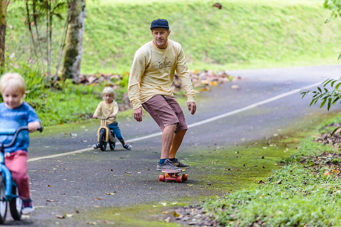 Father on skateboard accompanying sons on bicycles