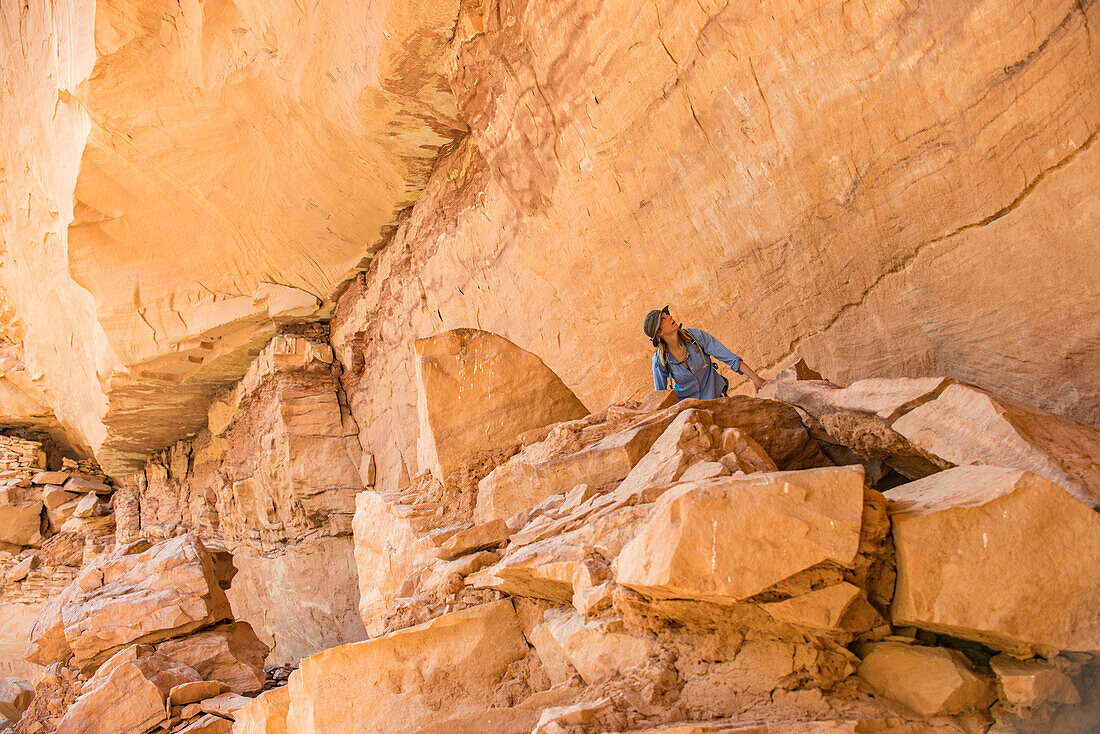 Woman looking at Green Mask pictographs, Sheiks Canyon, Grand Gulch area of Bears Ears National Monument, Utah, USA