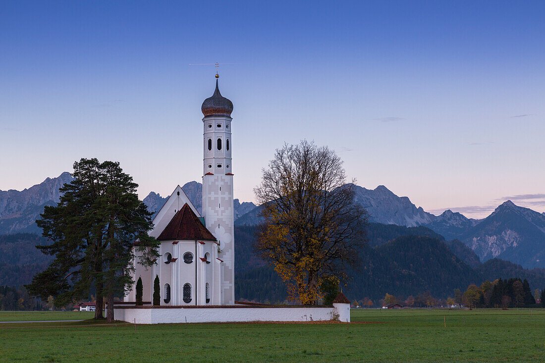 Sunrise on St Coloman Church surrounded by woods. Schwangau, Fussen, Bavaria, Southwest Bavaria, Germany, Europe.