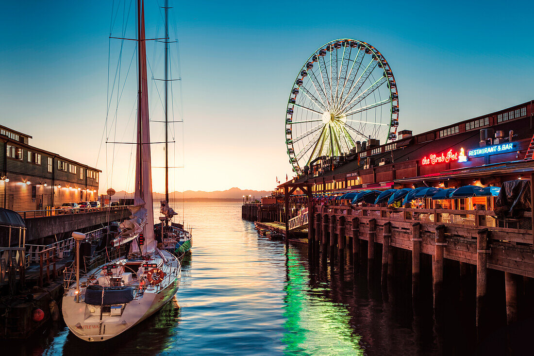 Sunset over mountains with Seattle Great Wheel on Pier 57 in the foreground. Seattle, Washington State, United States of America, North America