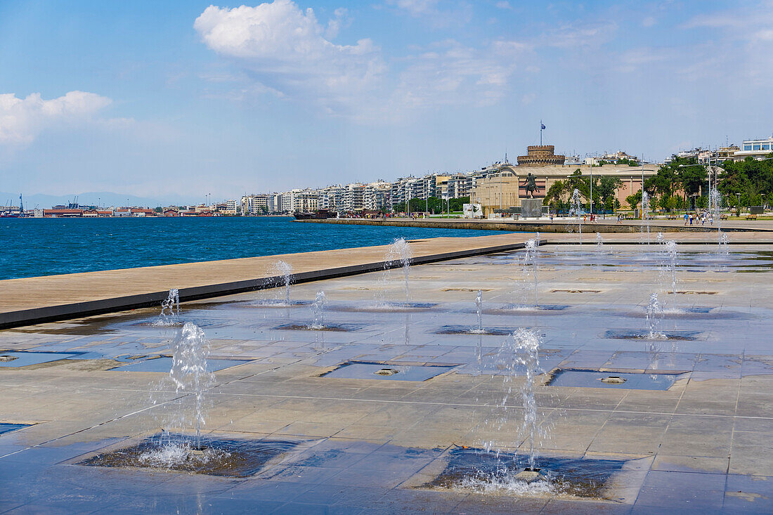 Waterfront view of fountains at umbrellas area, statue of Alexander The Great and city's landmark White Tower, Thessaloniki, Greece, Europe