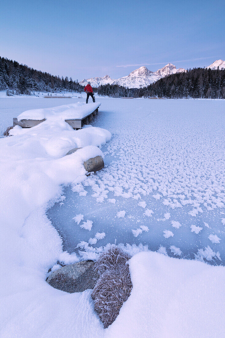 Man standing on the shore of frozen lake, Lej da Staz, St. Moritz, Engadine, Canton of Graubunden (Grisons), Switzerland, Europe