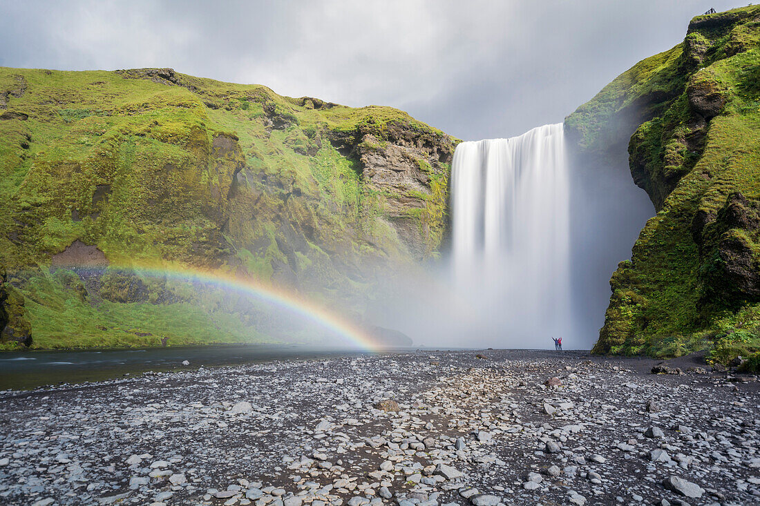 Double rainbow and tourists with hands in the air at Skogafoss waterfall in South Iceland, Polar Regions