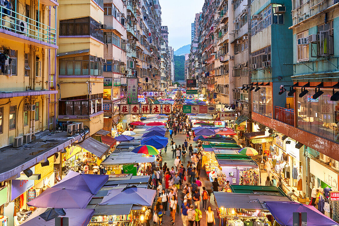 A busy market street in Mong Kok (Mongkok) lit up at dusk, Kowloon, Hong Kong, China, Asia