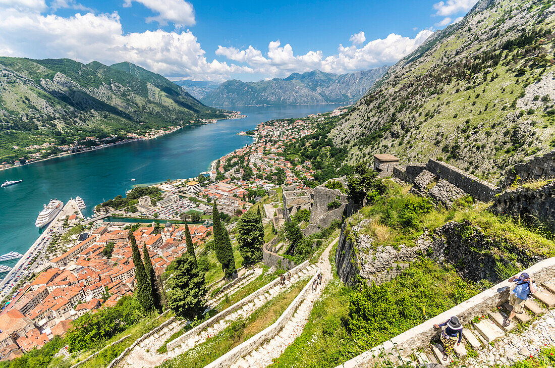 Hikers walking the old city walls during the daytime above the Bay of Kotor, UNESCO World Heritage Site, Montenegro, Europe