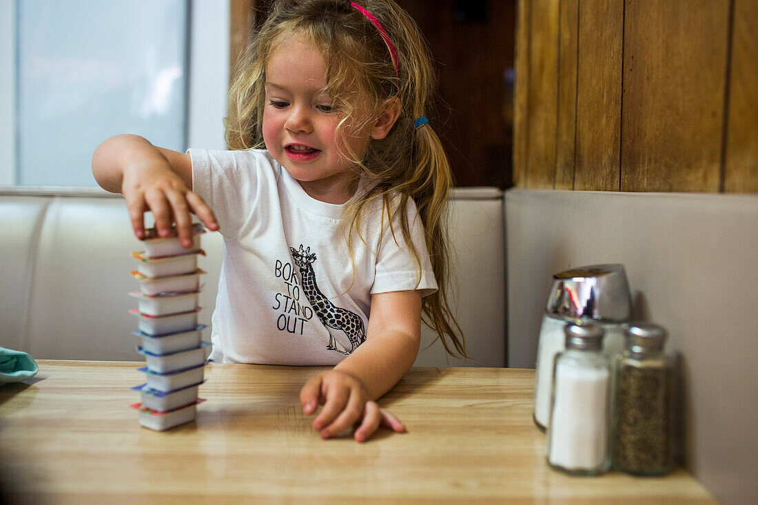 Smiling Caucasian girl stacking jelly containers in restaurant booth