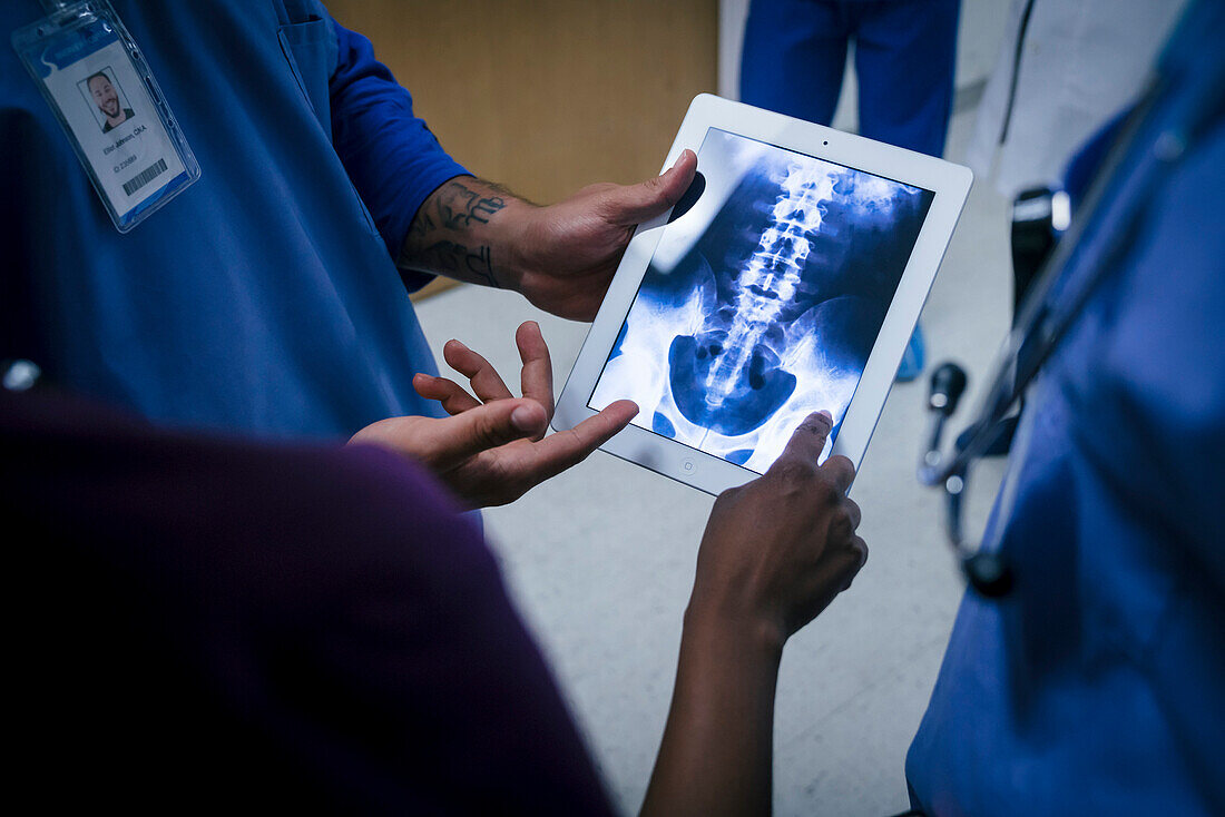 Doctors examining x-ray of pelvis and spine on digital tablet