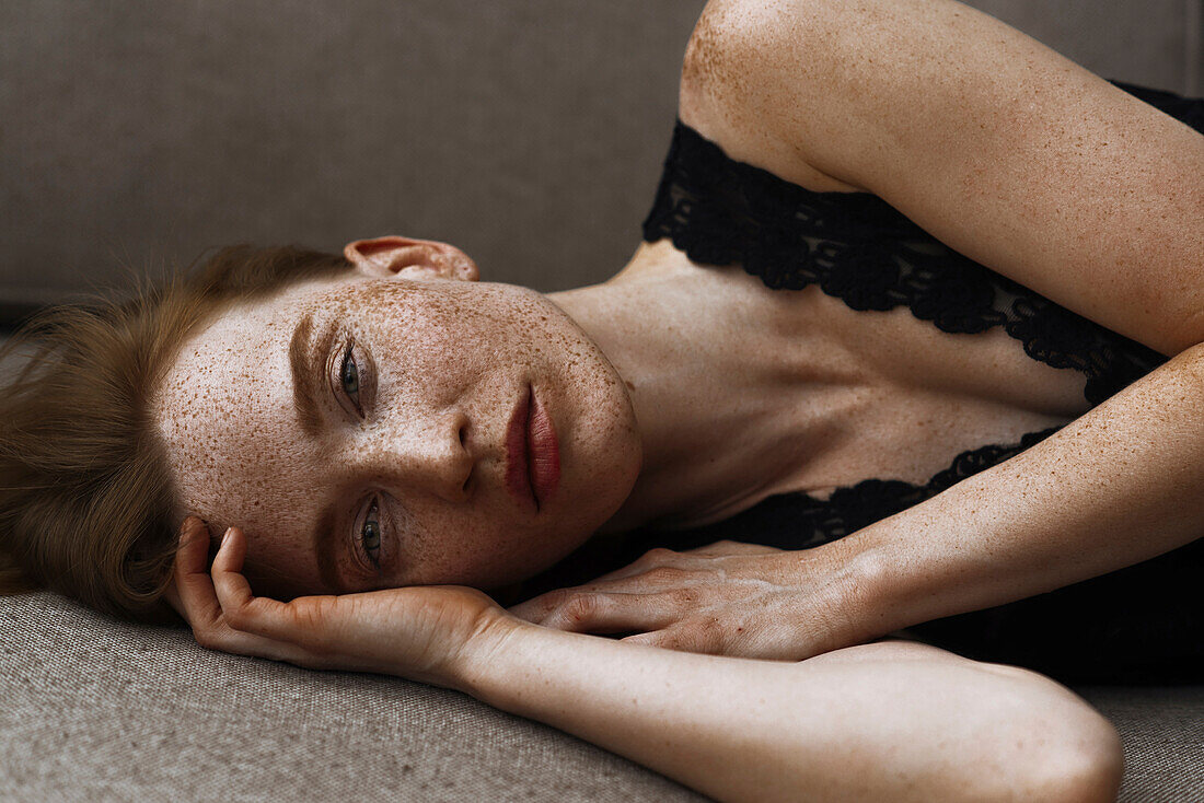 Pensive Caucasian woman with freckles laying on floor