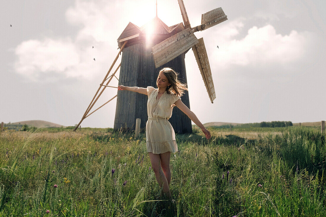 Caucasian woman balancing in grass near windmill