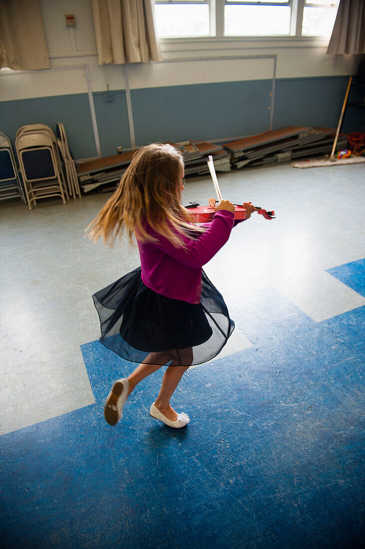 Caucasian girl practicing violin and dancing