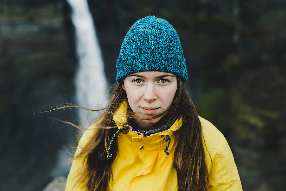 Wind blowing hair of Caucasian woman near waterfall