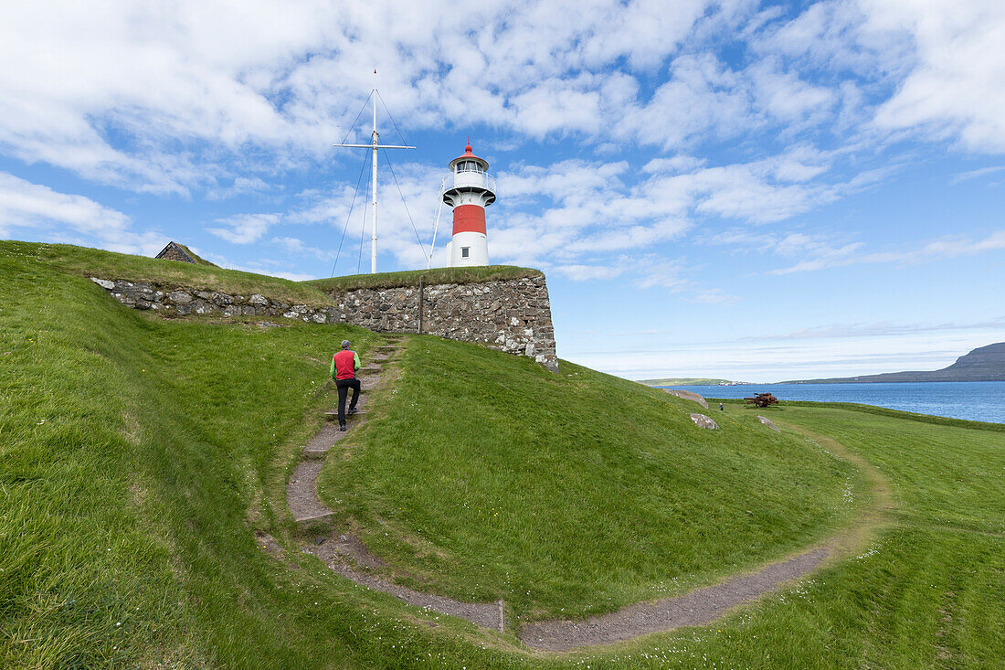 Man walks to the lighthouse and historic fortress of Skansin,Torshavn, Streymoy Island, Faroe Islands, Denmark, Europe